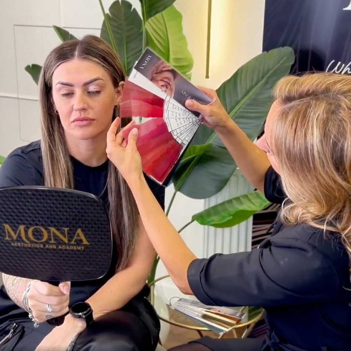 Artist holding up lip pigment color swatches to a client face