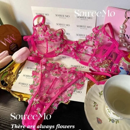 Pink floral lingerie set with 'SourceMo' branding on a table with a cup and saucer.