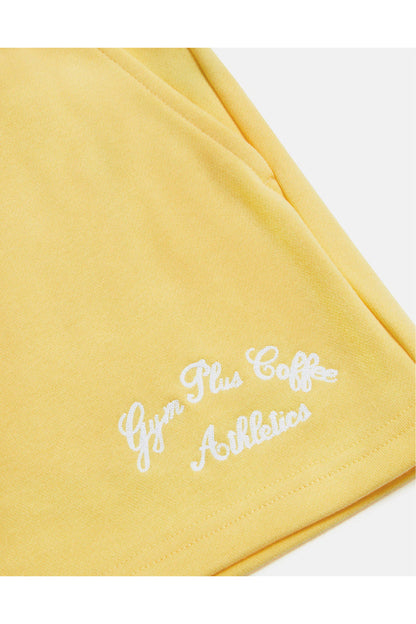 Close-up of embroidered Gym+Coffee logo on Gym+Coffee Daily Cotton Shorts in Lemon Sorbet, shop Gym+Coffee at Dotique