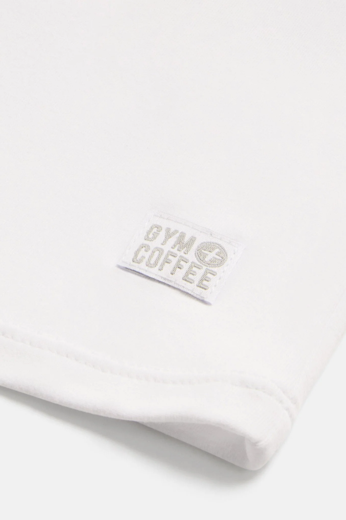 Close-up of the Gym+Coffee Daily Urban Tee in Ultra White showing the Gym+Coffee logo, shop the vendor at Dotique.
