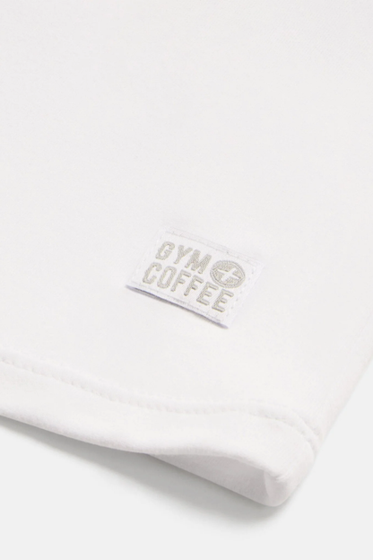 Close-up of the Gym+Coffee Daily Urban Tee in Ultra White showing the Gym+Coffee logo, shop the vendor at Dotique.