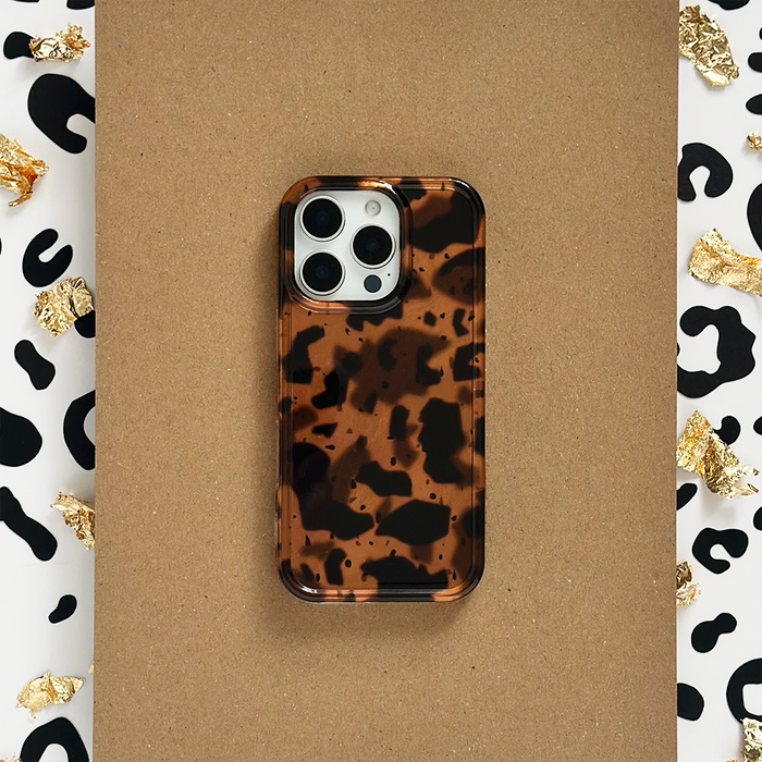 Leopard print phone case with gold foil accents, resting on a brown surface.