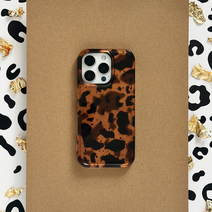 Leopard print phone case with gold foil accents, resting on a brown surface.