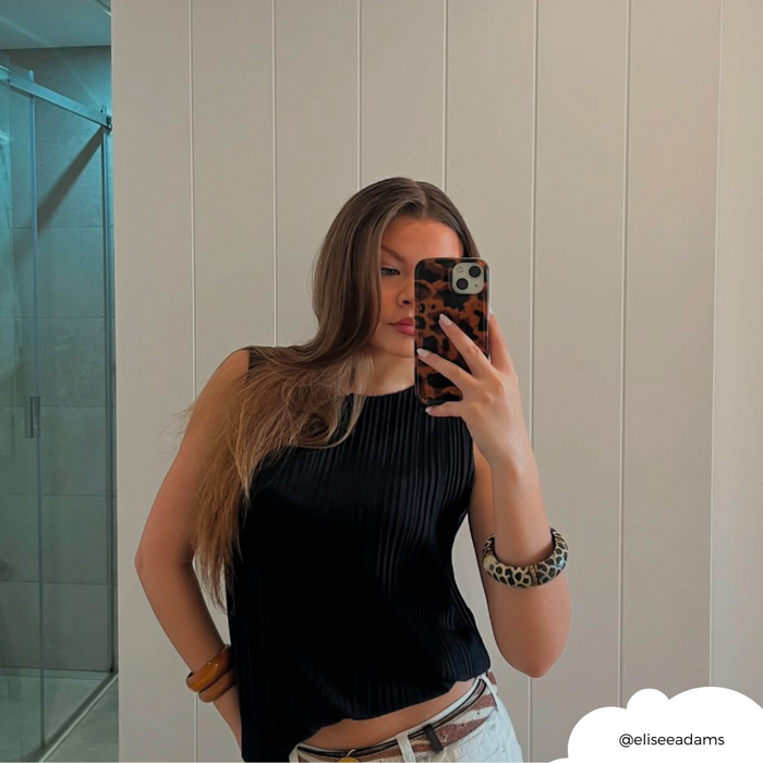 Woman with long hair wearing a black top holds a Coconut Lane phone case with a brown leopard tortoiseshell pattern.