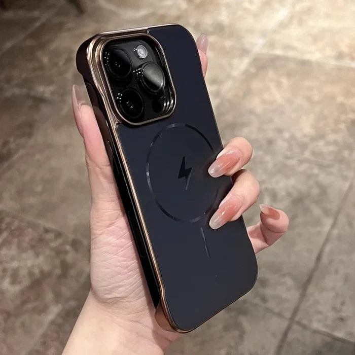 A person holding a dark smartphone in a case with gold edges and a circular magnetic charging symbol.